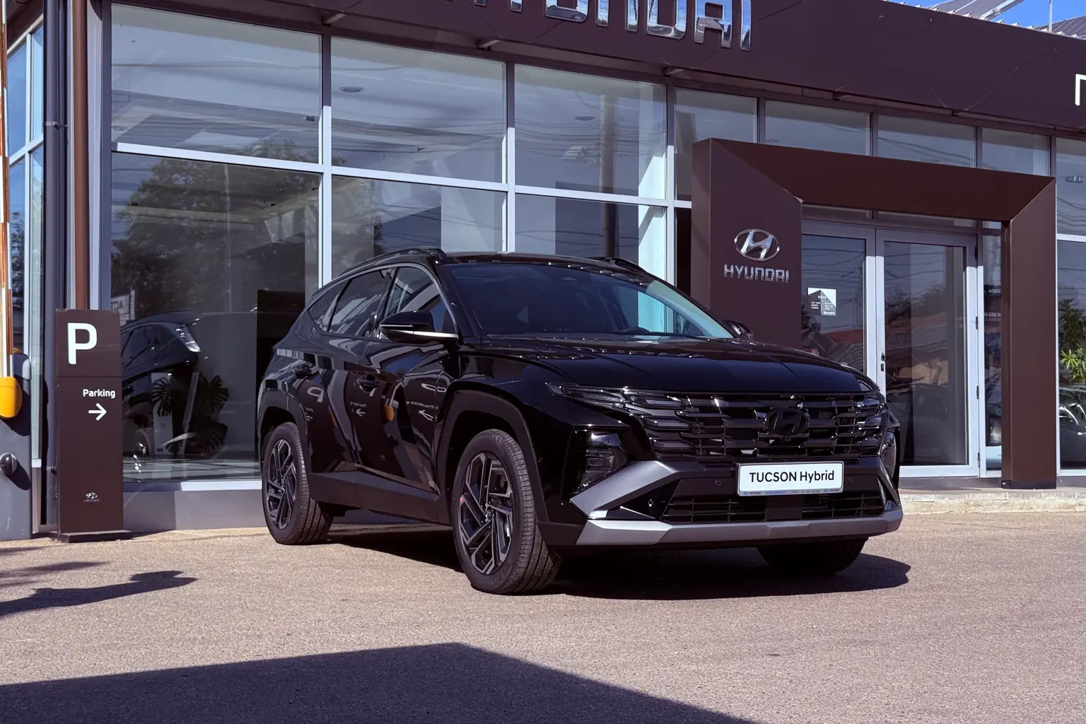Hyundai Tucson Hybrid nou, din stocul CarShift, parcat în fața unui showroom auto